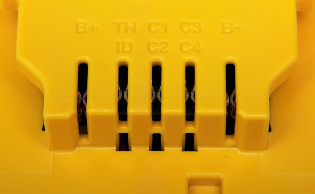 Como cuidar da bateria de ferramentas sem fio Contatos metálicos de uma bateria amarela de ferramenta sem fio