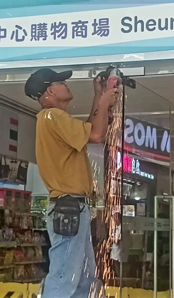 Pessoa usando uma esmerilhadeira angular em frente a uma loja